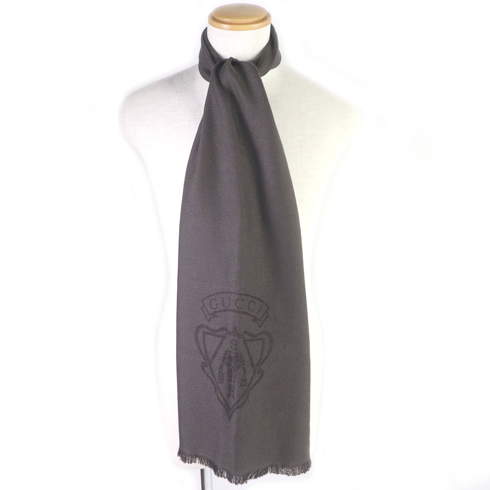 Gray scarf with a GUCCI brand logo on a mannequin against a white background